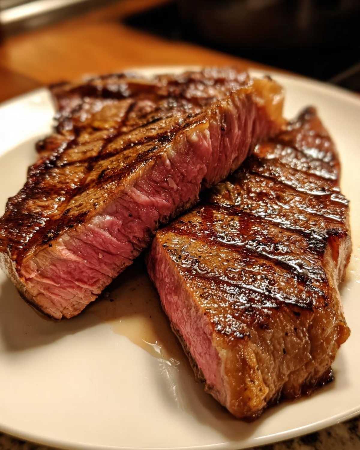 Dwa soczyste kawałki steka wołowego idealnego, przekrojone na pół, pokazujące idealnie różowe wnętrze medium-rare.