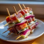 Zbliżenie na szaszłyki z szynką parmeńską, melonem, serem pleśniowym i czerwoną cebulą, idealne przekąski na ostatki.