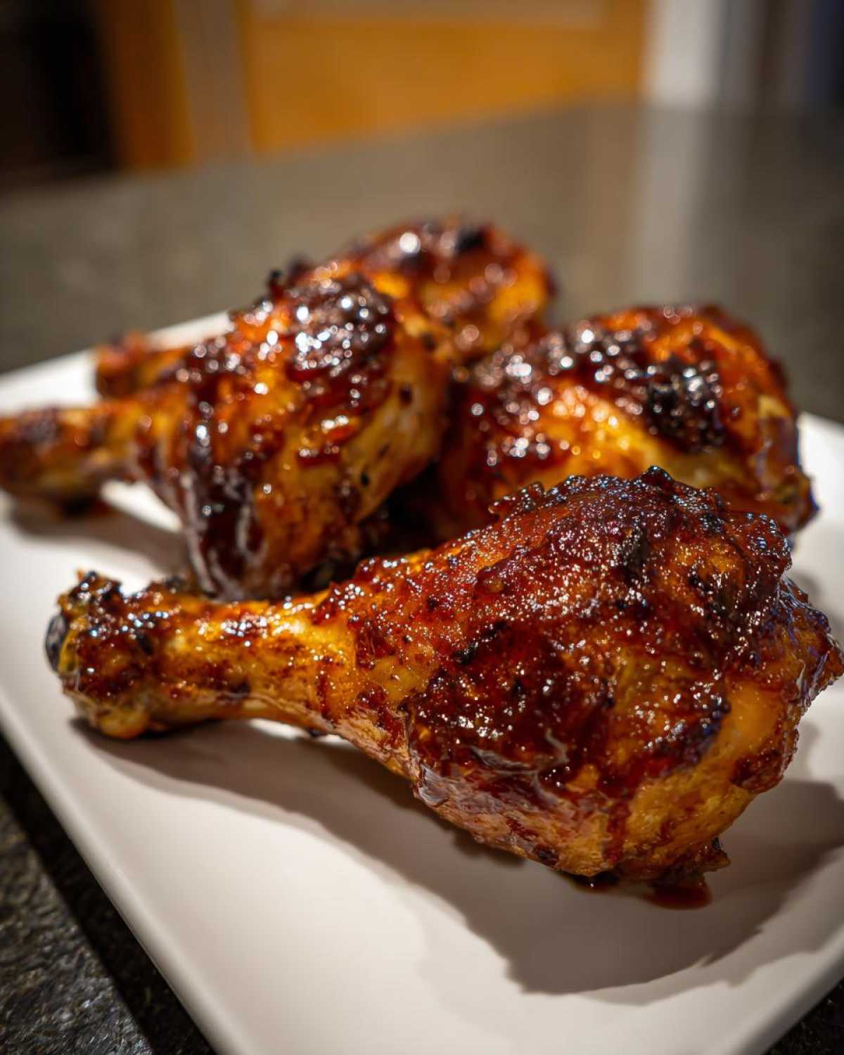 Zbliżenie na apetyczne, glazurowane udka z kurczaka w miodzie na białym talerzu.