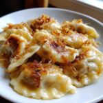 Zbliżenie na talerz pełen usmażonych pierogi z mięsem (z rosołu) posypanych chrupiącą cebulką.