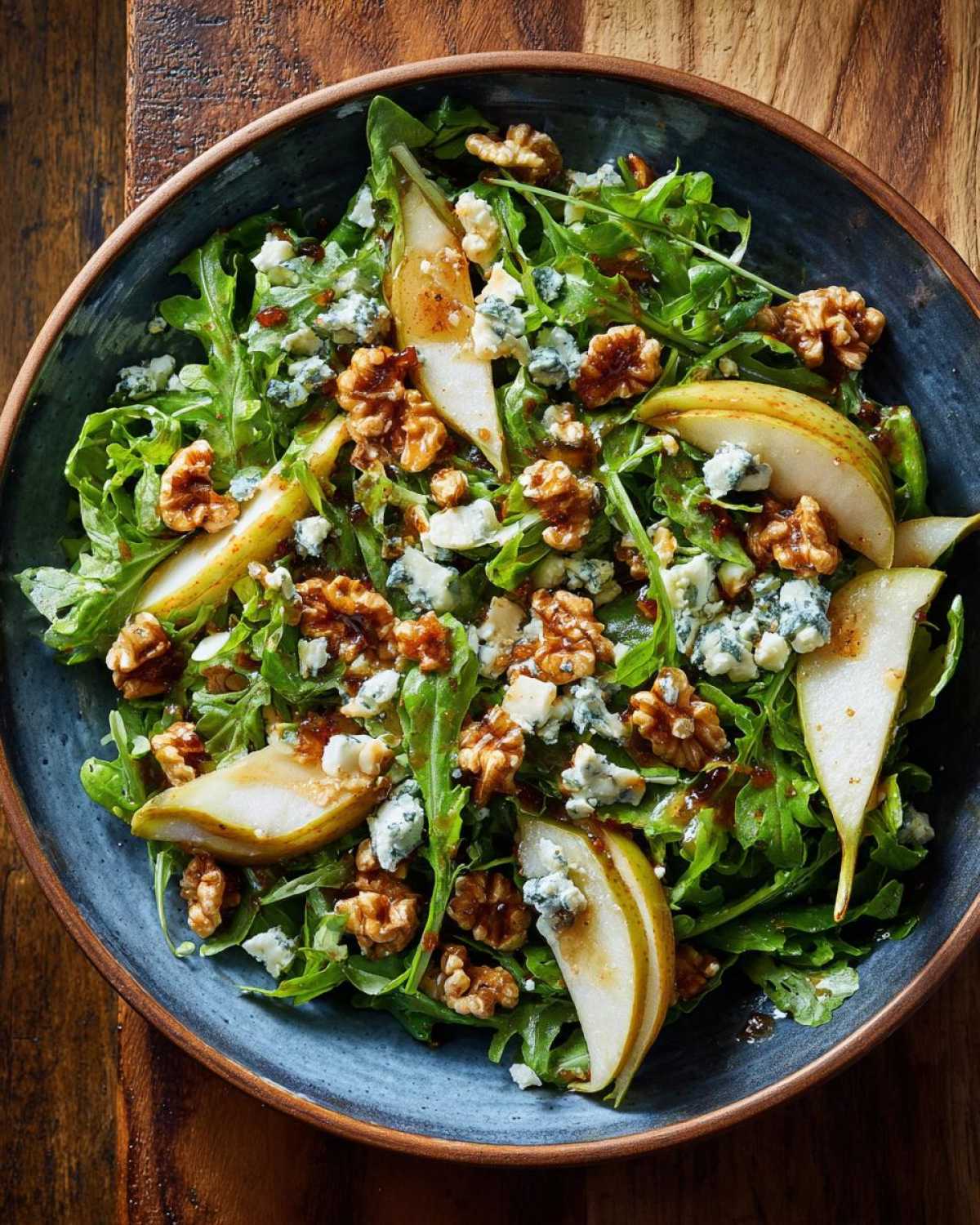 Zbliżenie na gotową Sałatka z rukolą, gruszką i serem pleśniowym w niebieskiej misce.