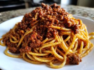 Zbliżenie na talerz pełen makaronu spaghetti polanego obfitą porcją sosu mięsnego Spaghetti Bolognese (wersja polska).