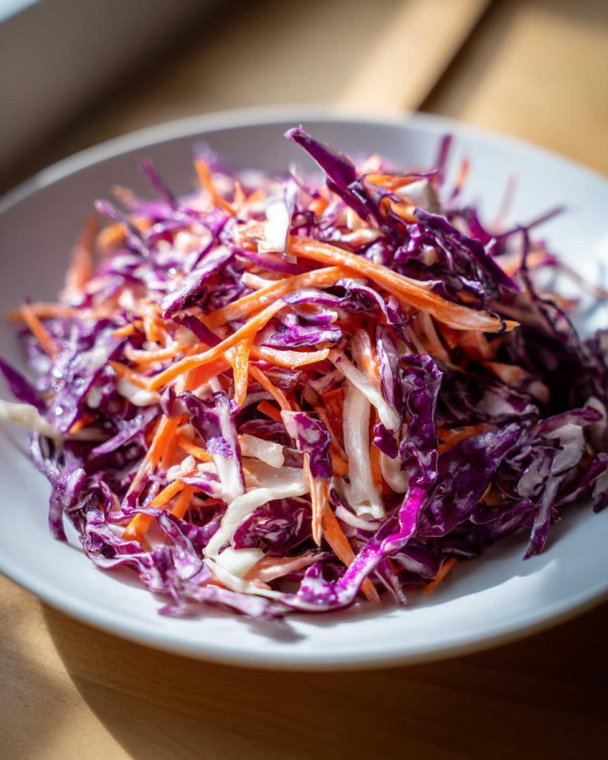 Zbliżenie na miskę pełną świeżej surówki z czerwonej kapusty surowej i startej marchewki.