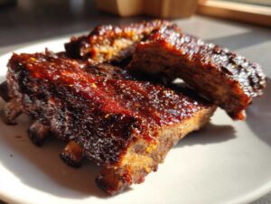 Zbliżenie na kawałki soczystych Żeberka BBQ pieczone, pokryte błyszczącym, karmelizowanym sosem.