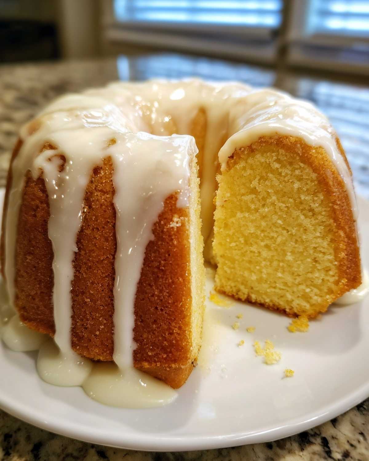 Apetyczna Babka cytrynowa z lukrem z wyciętym kawałkiem, ukazująca puszysty środek.