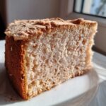 Zbliżenie na puszystą babkę piaskową z widoczną, lekką strukturą ciasta, podaną na białym talerzu.