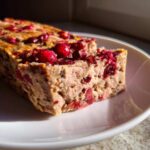 Przekrojony kawałek Domowy pasztet z królika z żurawiną na białym talerzyku.