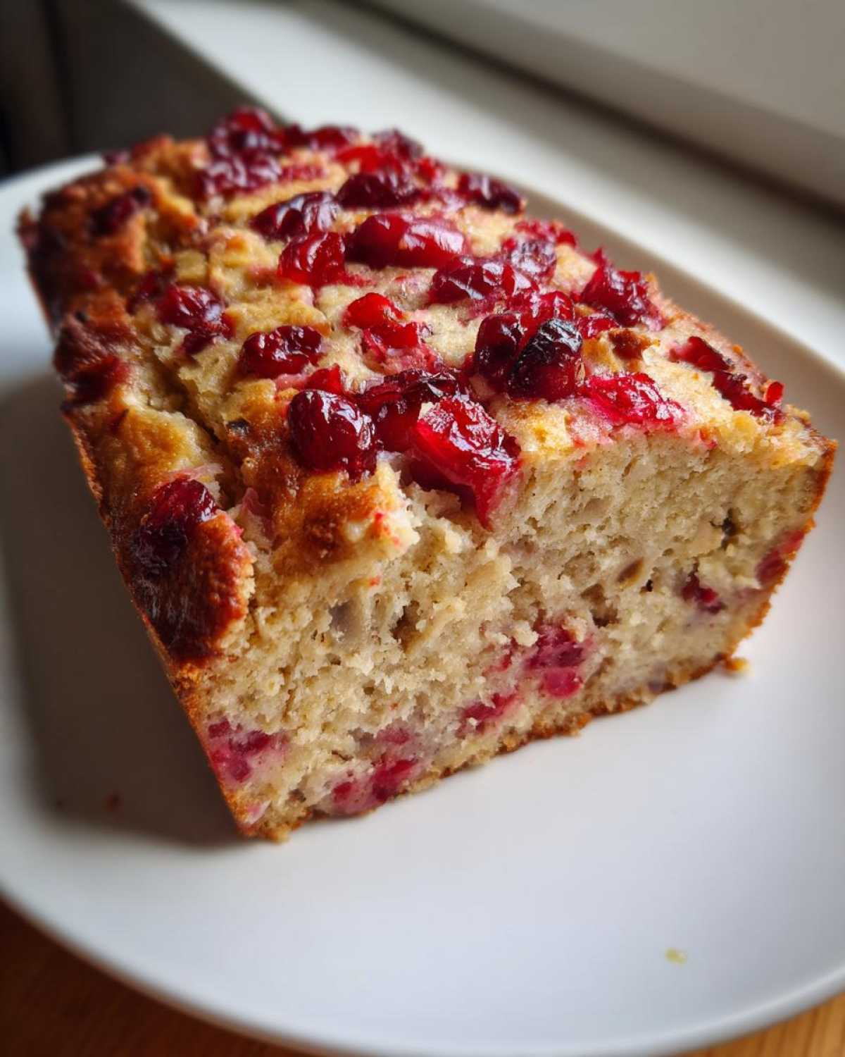Przekrojony kawałek ciasta z żurawiną, przypominający Domowy pasztet z królika z żurawiną.