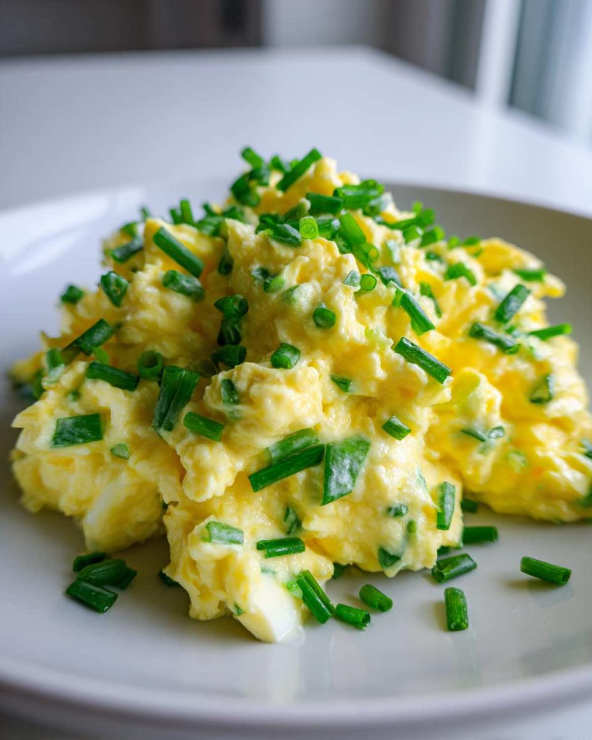 Kremowa klasyczna pasta jajeczna ze szczypiorkiem, obficie posypana świeżym, zielonym szczypiorkiem.