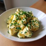 Zbliżenie na miskę pełną klasycznej pasty jajecznej ze szczypiorkiem, gęstej i kremowej.