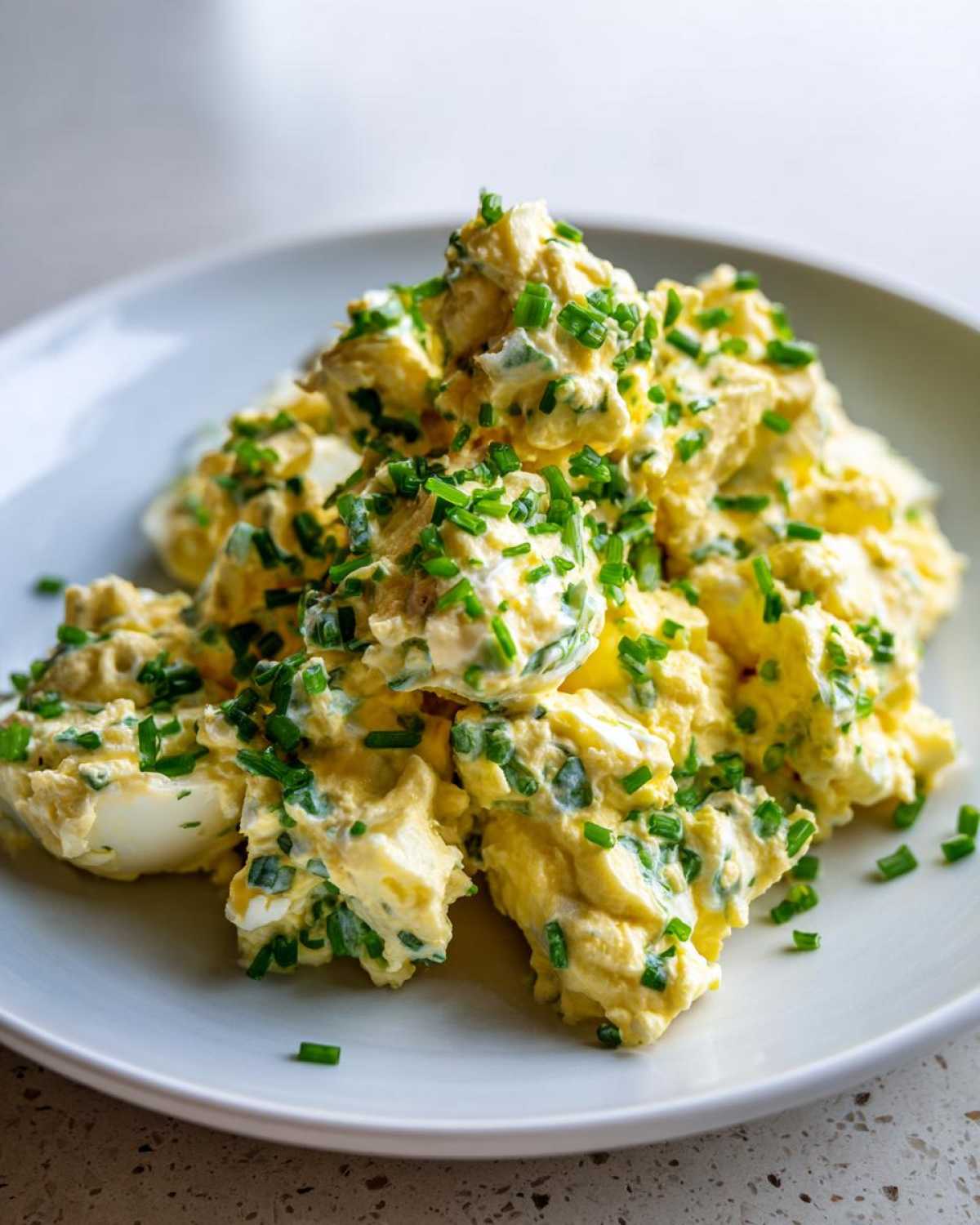 Zbliżenie na porcję Klasyczna pasta jajeczna ze szczypiorkiem obficie posypana świeżym szczypiorkiem.