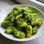 Zbliżenie na porcję włoskie gnocchi z domowym pesto bazyliowym w białej misce.