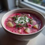 Miseczka Zupa botwinka z młodymi ziemniakami i świeżym koperkiem, udekorowana kleksem śmietany.