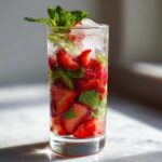 Szklanka pełna lodu, pokrojonych truskawek i mięty – idealne bezalkoholowe mojito truskawkowe.