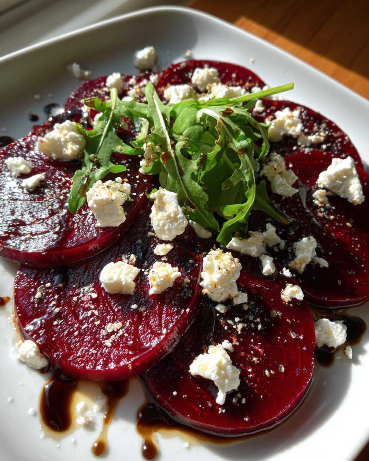 Plasterki Carpaccio z buraka z kozim serem, polane sosem balsamicznym i rukolą.