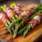 Zbliżenie na pyszne Grillowane szparagi z szynką parmeńską, podane na drewnianej desce.