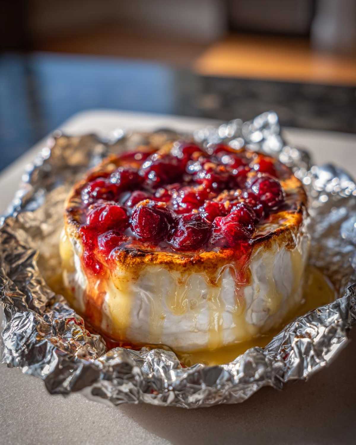 Zbliżenie na płynny Grillowany camembert z żurawiną, roztopiony ser wypływa na folię aluminiową.