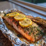 Soczysty Grillowany łosoś w folii aluminiowej udekorowany plasterkami cytryny i koperkiem.