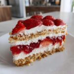 Kawałek puszystego Truskawkowa chmurka ciasto z warstwami biszkoptu, kremu i truskawek.