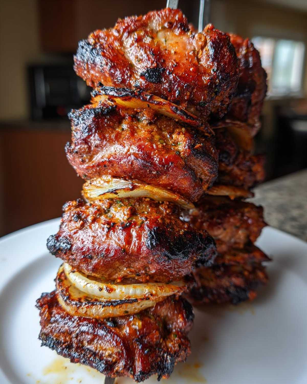 Zbliżenie na soczysty Kebab z karkówki z grilla ułożony na szpikulcu z kawałkami cebuli.