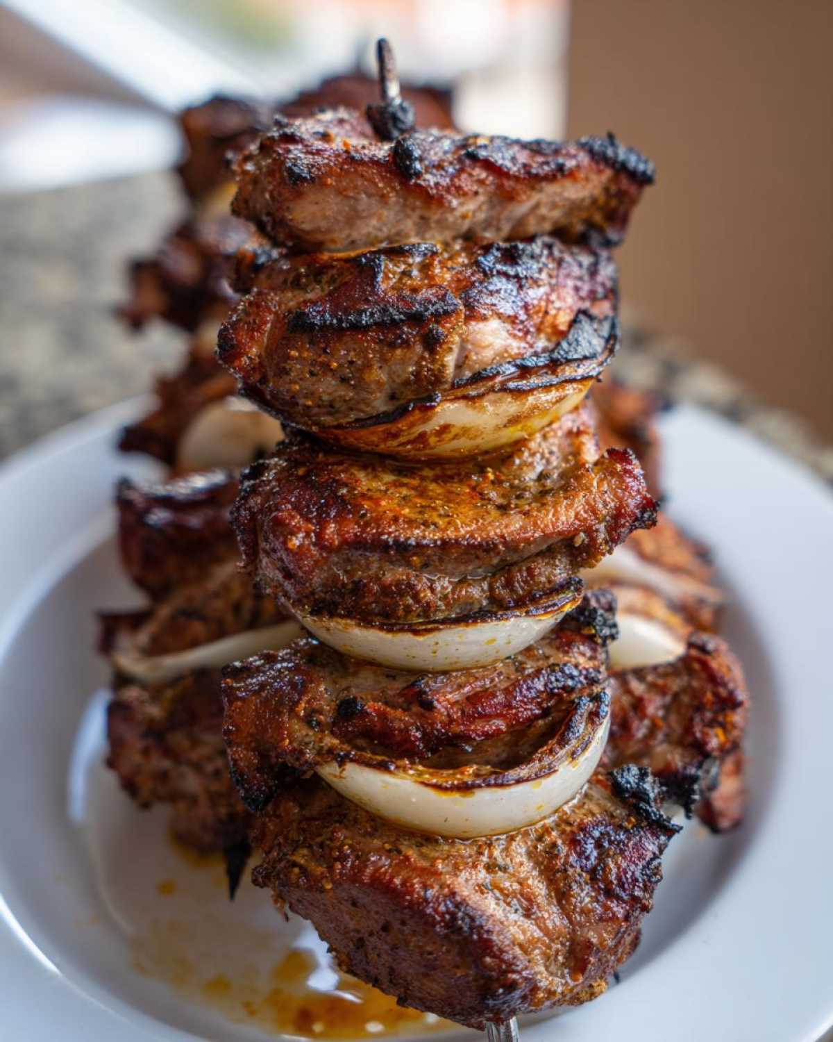 Zbliżenie na grillowany Kebab z karkówki z grilla ułożony na szaszłyku z kawałkami cebuli.