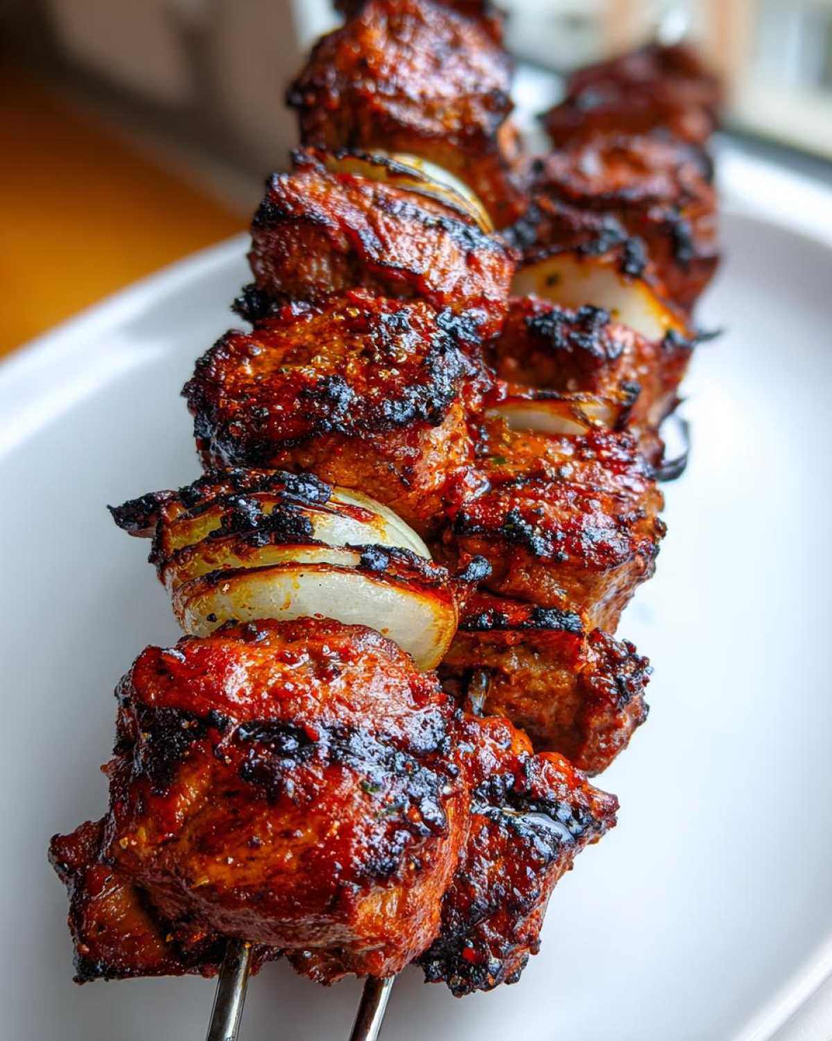 Zbliżenie na grillowany kebab z karkówki z cebulą na metalowym szpikulcu, idealny kebab z karkówki z grilla.