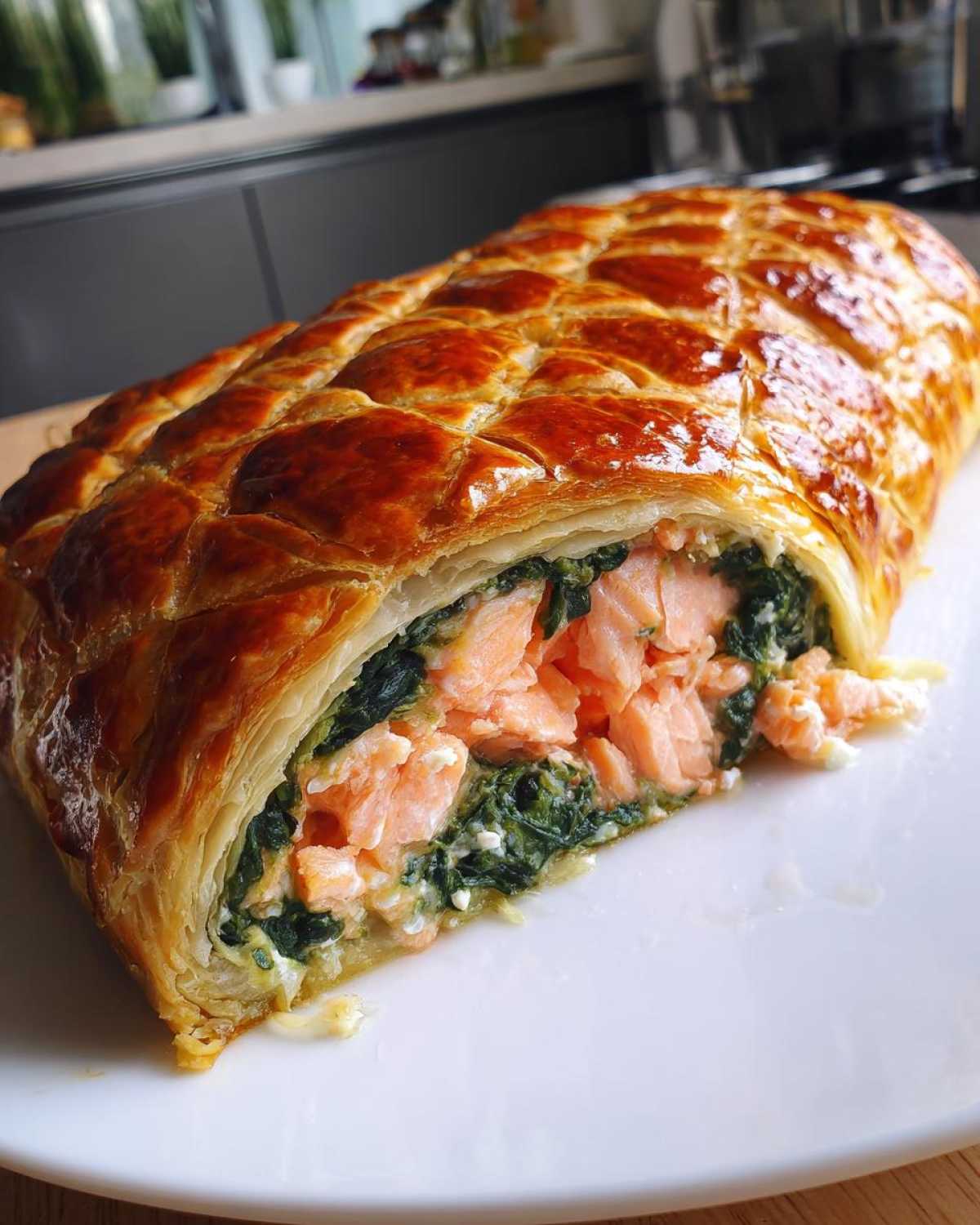 Zbliżenie na przekrojony Łosoś Wellington w cieście francuskim z łososiem i szpinakiem.