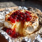 Płynny Grillowany camembert z żurawiną, z którego wypływa ser, podany na folii aluminiowej.