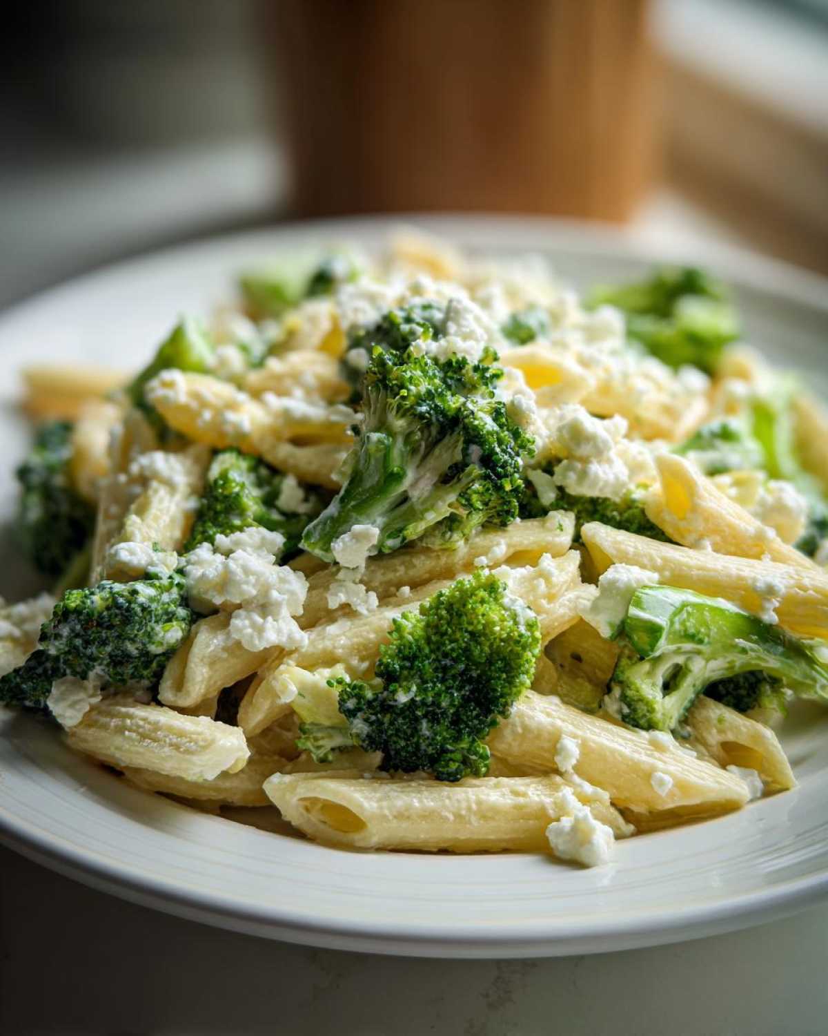 Zbliżenie na talerz pełen penne, brokułów i sera, idealna Sałatka makaronowa z brokułami.