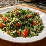 Zbliżenie na porcję Sałatka tabbouleh z kaszą bulgur, bogata w natkę pietruszki i pomidory.