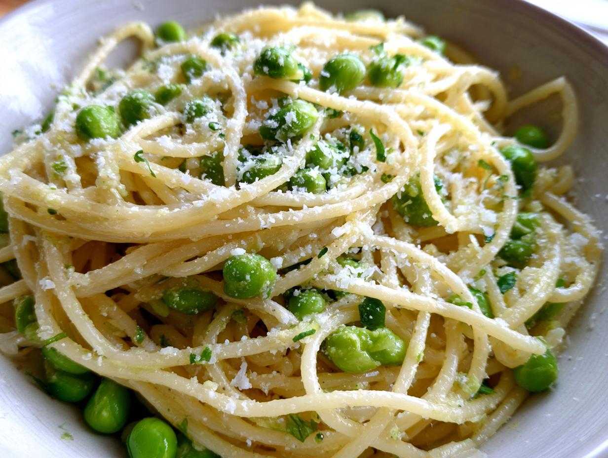 Zbliżenie na talerz pełen makaronu spaghetti z bobem, czosnkiem i startym parmezanem.
