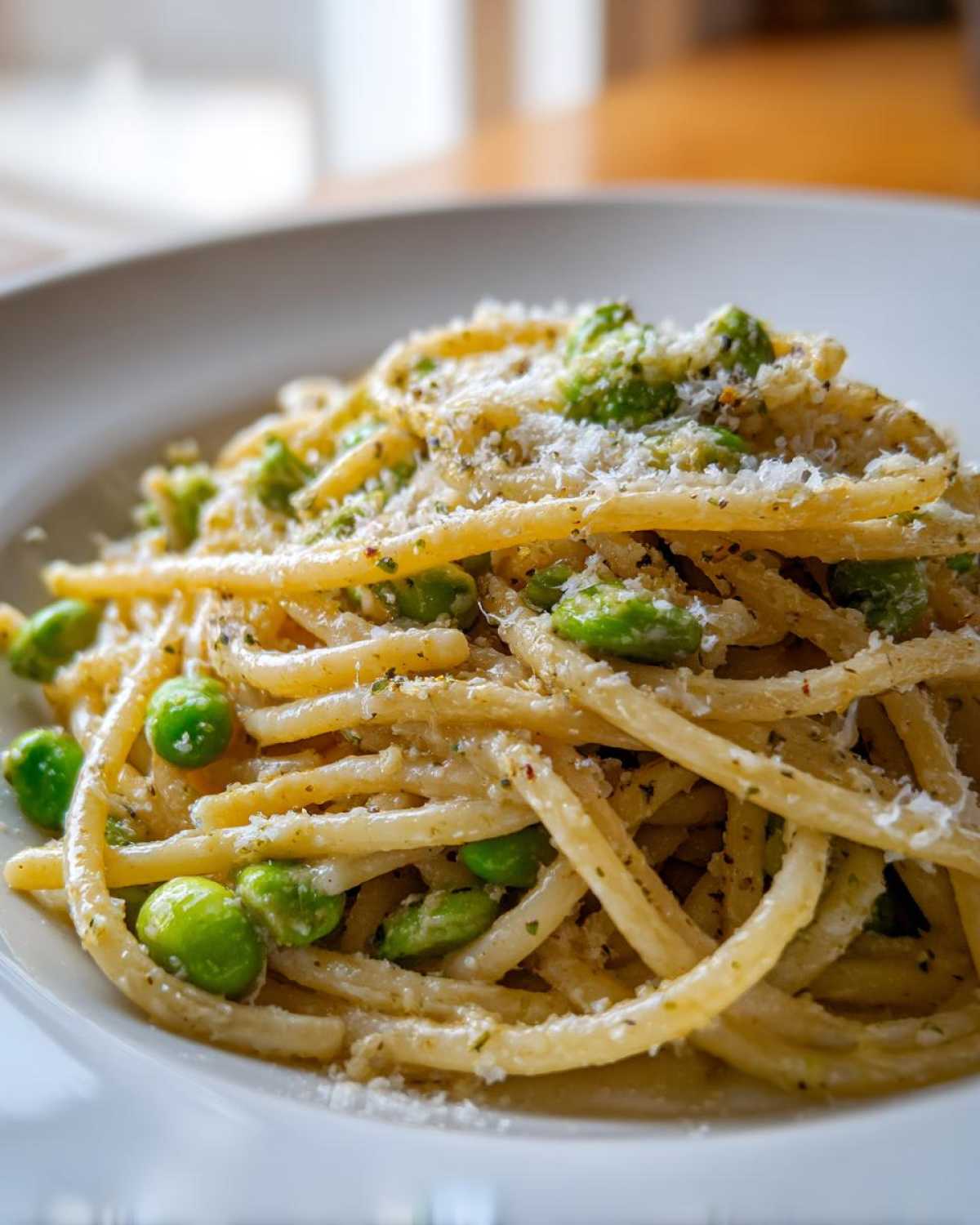 Zbliżenie na porcję Spaghetti z bobem czosnkiem i parmezanem posypane tartym serem.