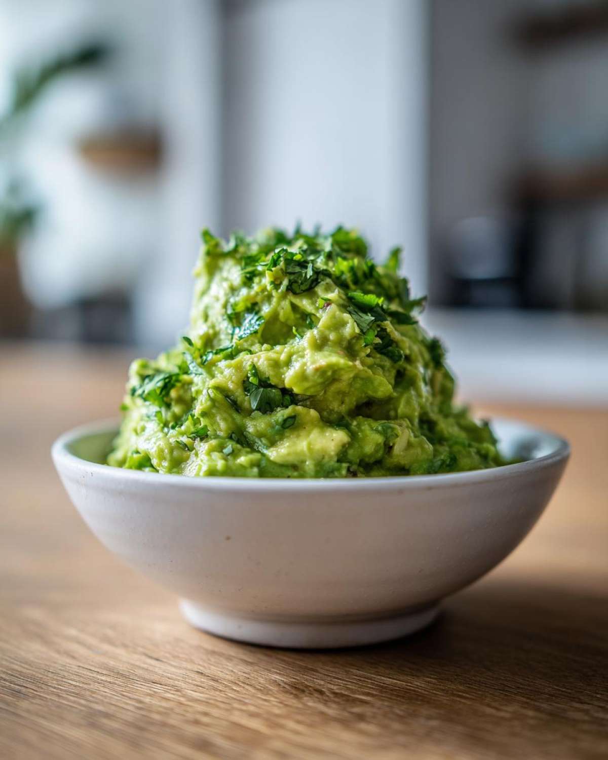 Gęste, świeżo przygotowane Guacamole do mięs z grilla posypane kolendrą w białej misce.