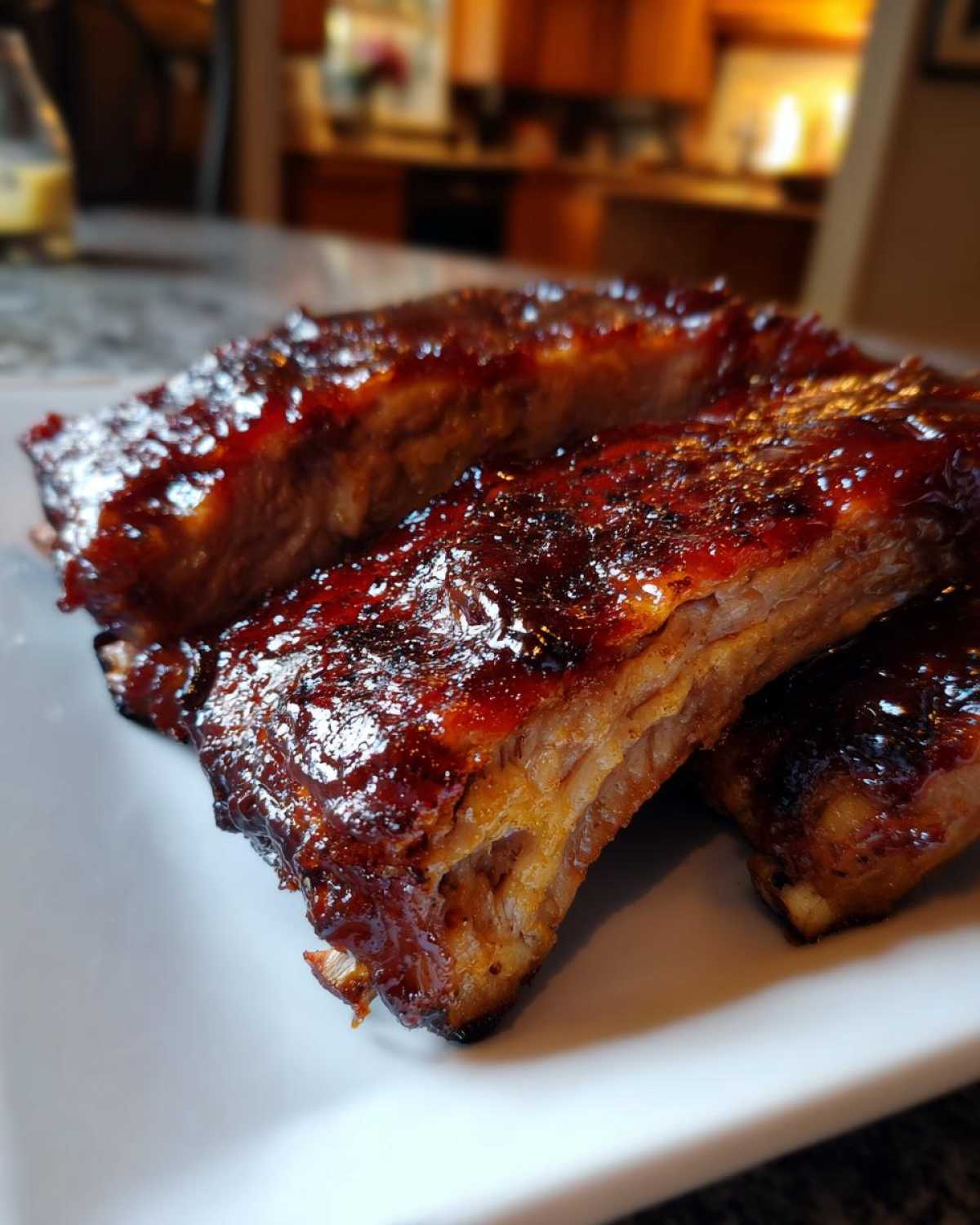 Zbliżenie na kawałki soczystych Żeberka BBQ z grilla polane gęstym, błyszczącym sosem.