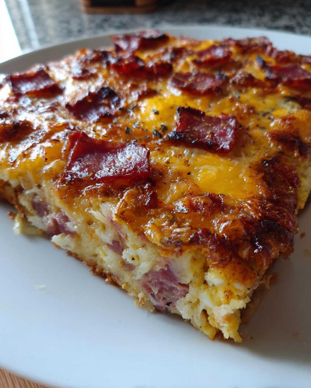 Kawałek zapiekane ziemniaki z serem i wędliną z chrupiącą, przypieczoną skórką na wierzchu.