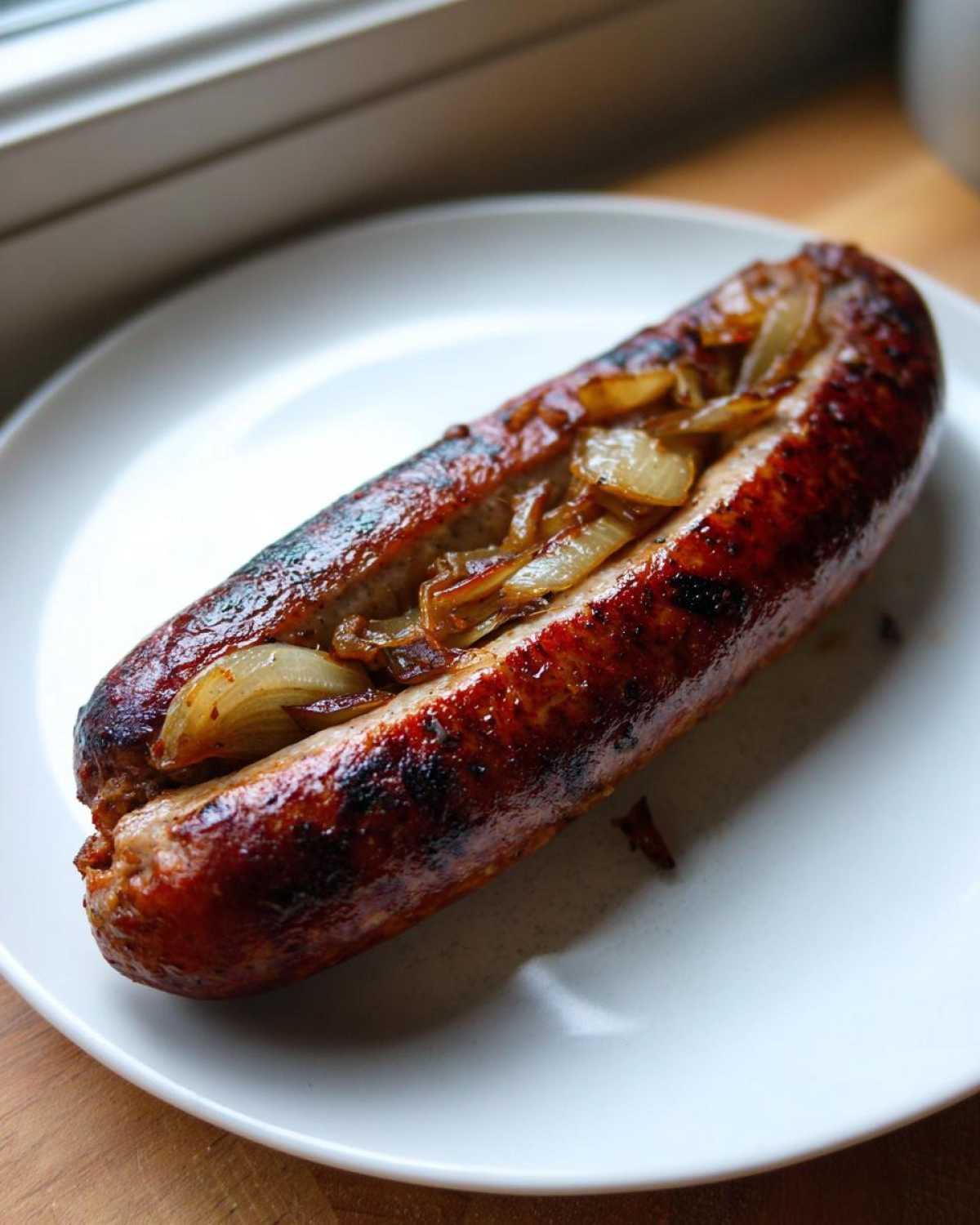 Apetyczna Kaszanka z grilla z jabłkiem i cebulą, podana na białym talerzu.
