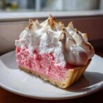 Kawałek tarta z rabarbarem i bezą włoską z różowym nadzieniem i przypieczoną bezą.