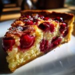 Zbliżenie na kawałek pysznej Tarta z czereśniami i migdałami, z widocznymi wiśniami i posypką z cukru pudru.