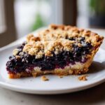 Kawałek soczystej Tarta z jagodami i kruszonką z grubą warstwą jagód i chrupiącą posypką.