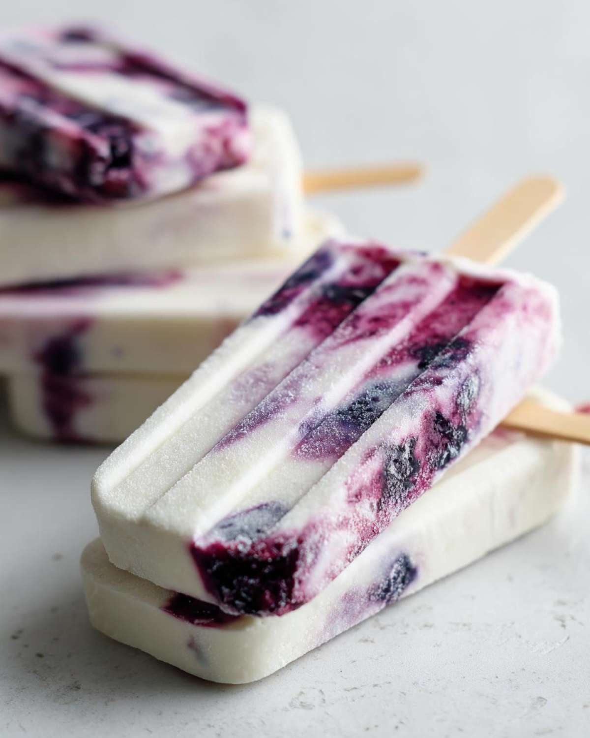 Zbliżenie na mrożone lody na patyku z jogurtu z widocznymi smugami jagód.