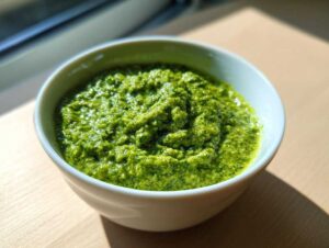 Gęste, intensywnie zielone Pesto z bobu z miętą i cytryną w białej miseczce.