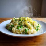 Porcja gorącego Risotto z bobem i cytryną, posypana skórką cytrynową i ziołami.