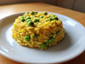 Porcja kremowego Risotto z bobem i cytryną uformowana na białym talerzu, z widocznym żółtym ryżem i zielonym bobem.