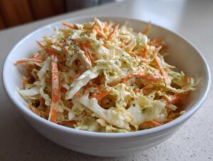 Zbliżenie na miskę pełną kremowej sałatki coleslaw z młodej kapusty i marchewki.