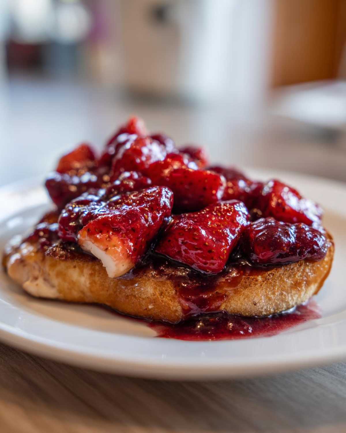 Zbliżenie na grzankę obficie polaną sosem i kawałkami truskawek, element przepisu Kurczak w sosie z truskawek i octu balsamicznego.
